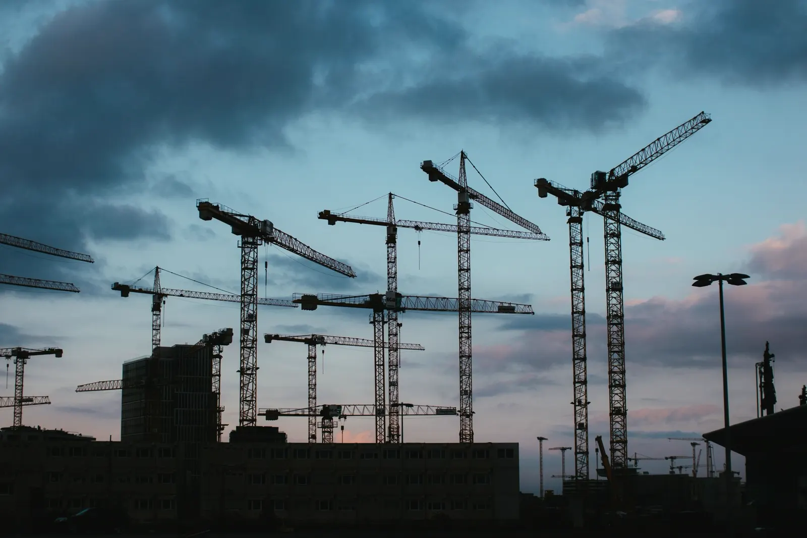 Toronydaruk sziluettje egy budapesti építési terület fölött, alkonyati égbolt előtt